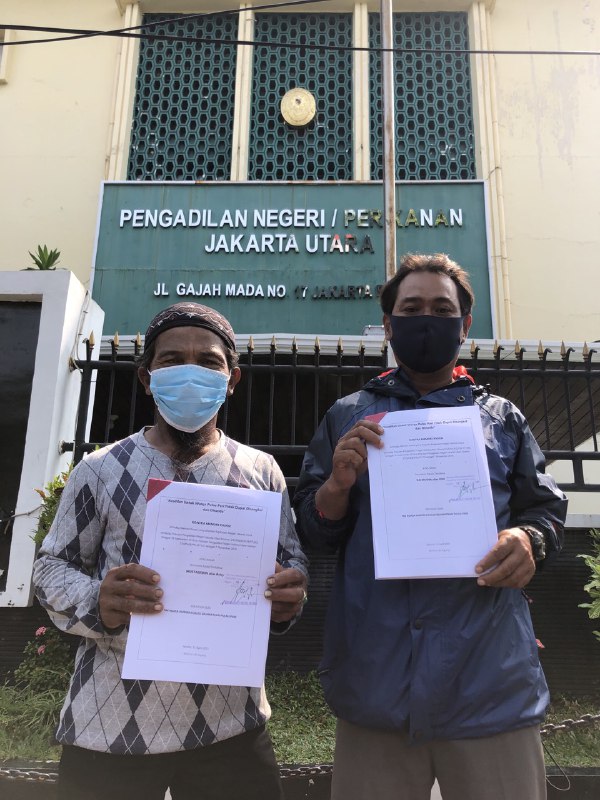 Foto warga pulau pari memegang kertas gugatan di depan Pengadilan Negeri Jakarta Utara