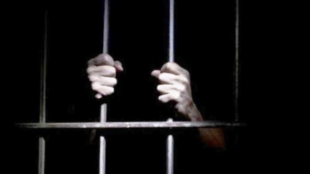 Foto tangan memegang jeruji penjara