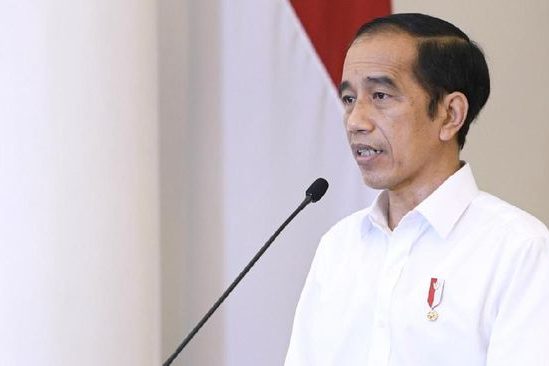 Jokowi menjelaskan Perppu Cipta Kerja menggunakan baju putih berdiri di podium